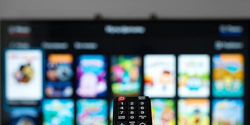 Person holding TV remote using streaming services